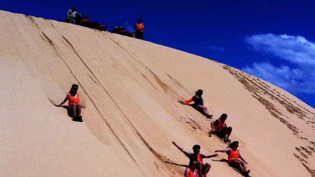 Sand boarding down the dunes of the Worimi conservation lands.