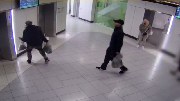 The man (centre) is seen waiting for a lift with two others, in CCTV footage.