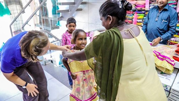 Krishna holds up a dress her to daughter Divya while shopping for supplies.