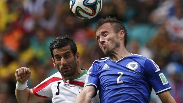 Iran's Ehsan Hajsafi jumps for the ball with Bosnia's Avdija Vrsajevic.