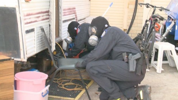 Police inspect the DMT-making equipment found during the raid.