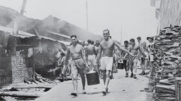 Liberated POWs at Changi carrying a bucket of rice from the mess. The inquiry is investigating recognition for prisoners killed while escaping Japanese camps.