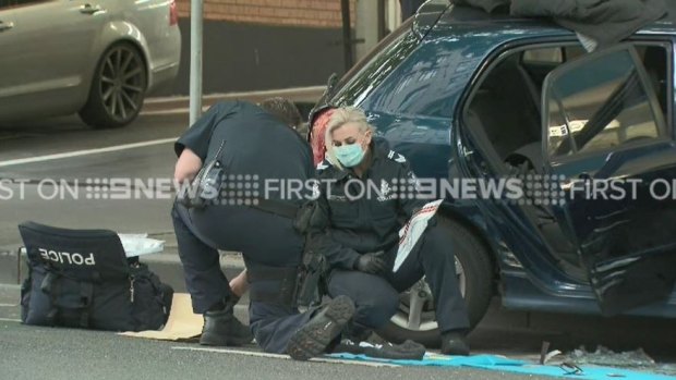 Police examine the car after it mounted the footpath on Bourke Street.