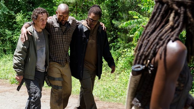 Michonne (Danai Gurira), right, watches as Nicholas (Michael Traynor), left, and Heath (Corey Hawkins) help the injured Scott (Kenric Green) in <em>The Walking Dead.</em>
