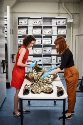 Museums Victoria's Objects Conservator Charlotte Walker (L) and Humanities Collections Manager Hannah Perkins with a dress from the archive.
