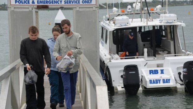 Two passengers from the stricken Firebird leave a rescue boat at Cleveland with a Queensland Ambulance Service officer.