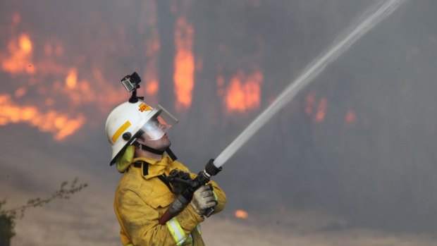 A firefighter directs water on a hotspot during the Winmalee/Springwood bushfire in 2013 in which almost 200 homes were destroyed. 