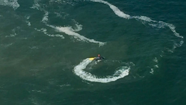 A man searches for the missing swimmer on a jet ski.