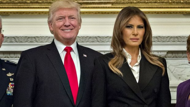 President Trump positions himself behind his wife, Melania, as they pose for the group photo. 