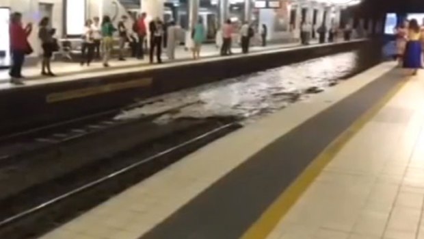 Shocked commuters watch rising floodwater cover the tracks at Fortitude Valley Station.