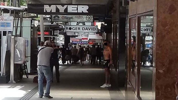 Shoppers hide while police negotiate with Hillier during the Queen Street Mall lockdown.