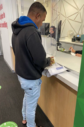 Thambirajah handing over bundles of cash to a bank teller. 