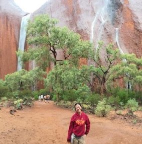 A tourist celebrates Uluru waterfalls. 