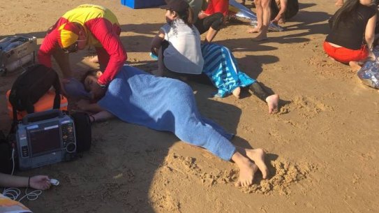 Birubi Point Surf Life Saving Club members and NSW Ambulance paramedics treating the swimmers at Birubi Beach.