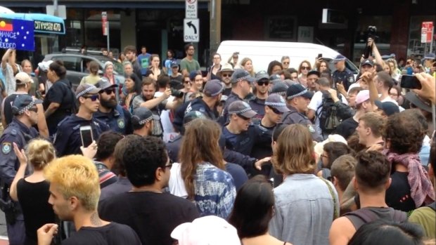 A group of police begins to back away from the crowd of protesters.