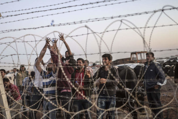 Syrian Kurds try to grab water thrown from Turkey near the border with Syria as they wait to take care of their animals in the south-eastern town of Suruc.