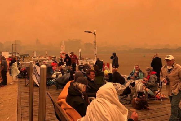 Locals and tourists on the Mallacoota wharf as bushfires surrounded the Victorian summer holiday spot on New Years Eve. Such scenes might become more commonplace.