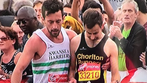 Matthew Rees, left, helps David Wyeth in the final stages of the London Marathon.