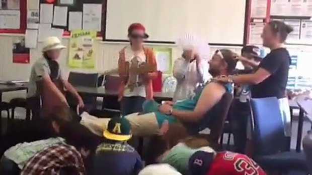 A still from the video where students are massaging former Caulfield Junior College teacher Chris Adams and bowing to him