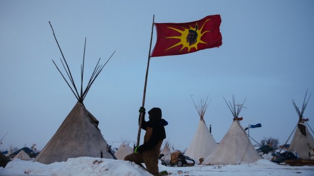 An unidentified man removes a Mohawk Warrior Society flag from his campsite at the Oceti Sakowin camp. The The Mohawk flag came to prominence during the 1990 Canadian Oka Crisis, when the military confronted indigenous people in a major armed conflict for the first time in modern history. .