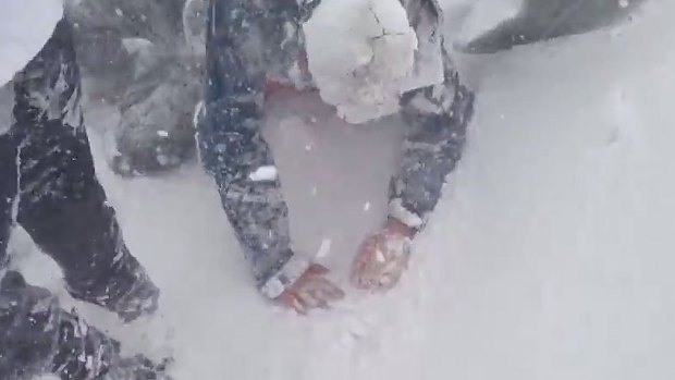 A person attempts to get to their feet after the avalanche swept through.