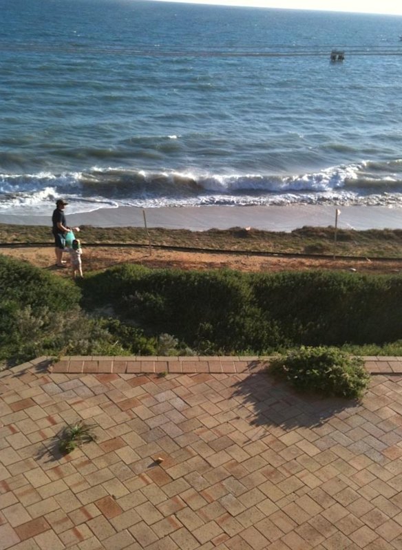 Ms Clifton's husband and daughter where the road once was. The land now drops away within a metre of their paved front yard.