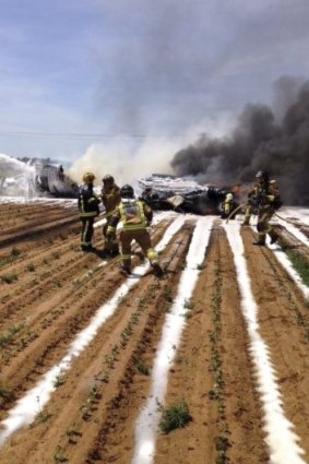 Firefighters try to extinguish a fire from an Airbus A400M after it crashed in a field near Seville, killing four people.