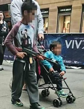 A boy walks through Martin Place with a toy AK-47.