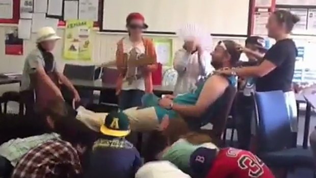 A still from a video in which students massage former Caulfield Junior College teacher Chris Adams and bow to him