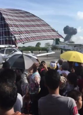 The crowd watches as smoke rises from the crash of a Gripen jet at Hat Yai Airport.