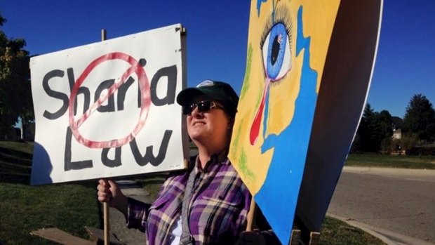 The protester, known only as Annie, with her signs outside the Noor Islamic Cultural Centre.