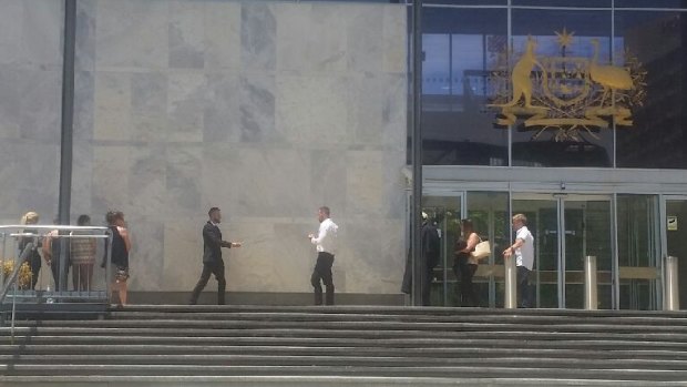 Paul James McCauley, 24, hands a cigarette to Christopher Johnston, 26, outside the ACT Supreme Court after a jury found them both guilty of importing a marketable quantity of cocaine.