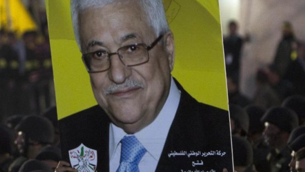Palestinians hold up a poster showing President Mahmoud Abbas on December 31, as they celebrate the 50th anniversary of the founding of the armed wing of the Fatah movement, al-Asifa, in Ramallah.