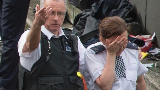 A police officer is led away by a colleague at the scene.