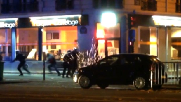 Sparks can be seen as bullets ricochet by a car near the Bataclan theatre.