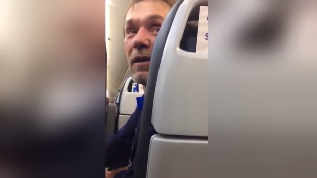 An image from a video a passenger on the United flight filmed of a man and woman being escorted off of the plane after he allegedly harassed a man and woman from Pakistan.