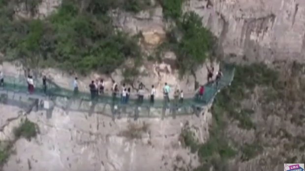 Tourists walking along the new glass walkway at Yuntai Mountain. 