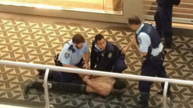 Restrained: Police subdue a man after the stabbing.