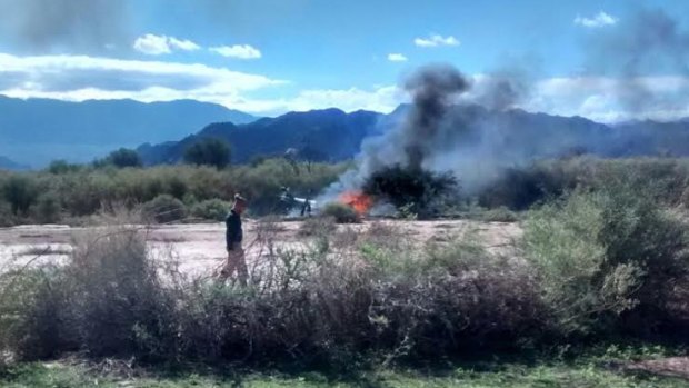 A man stands near the smoking remains of a helicopter that crashed with another near Villa Castelli in the La Rioja province of Argentina.
