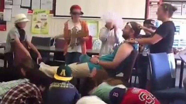 A still from a video in which students massage former Caulfield Junior College teacher Chris Adams and bow to him