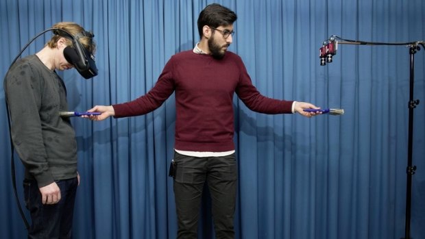 Study co-author Zakaryah Abdulkarim creates the invisible body illusion on a participant wearing a set of head-mounted displays connected to a pair of cameras (right).
