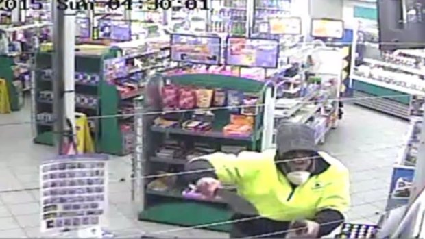 This image from CCTV footage shows the robber brandishing a knife at the counter.