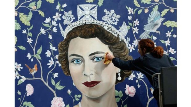 Workmen install a new mural, by Frederick Wimsett, of Queen Elizabeth II to mark her 90th birthday celebrations in central London.