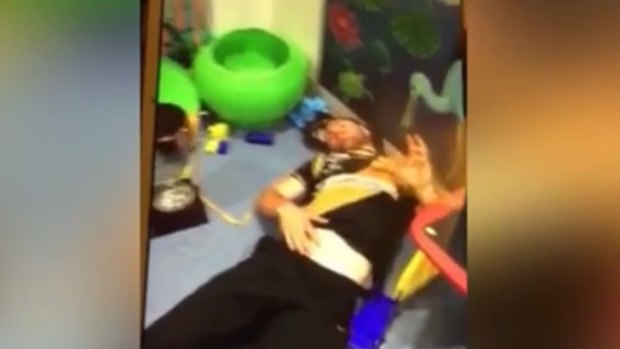 An Albury Tigers player on the floor of a children's play area in the hospital. 