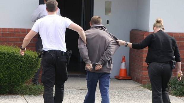 Detectives escort a 28-year-old man arrested over a Wynnum West home invasion into Cleveland Police Station on Wednesday afternoon. Photo by Stephen Jeffery