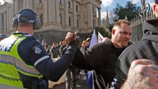 A Victorian police officer appears to give a Reclaim Australia supporter a solidarity handshake at a rally on Sunday.