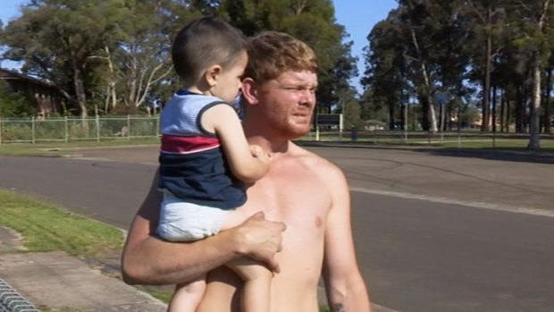 Corey holds his two-year-old son in season one of <i>Struggle Street</i>.