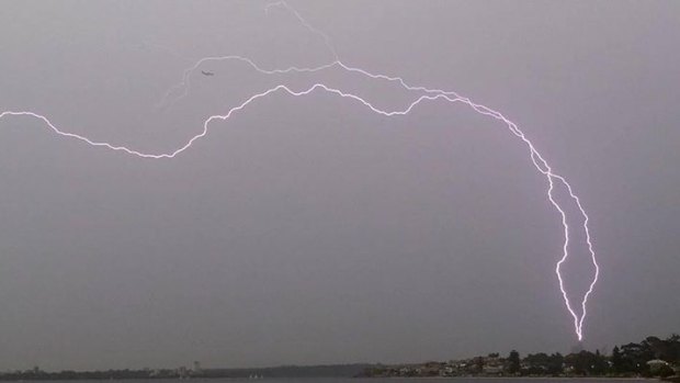 Lightning seems to threaten a plane and the BHP tower over Perth.