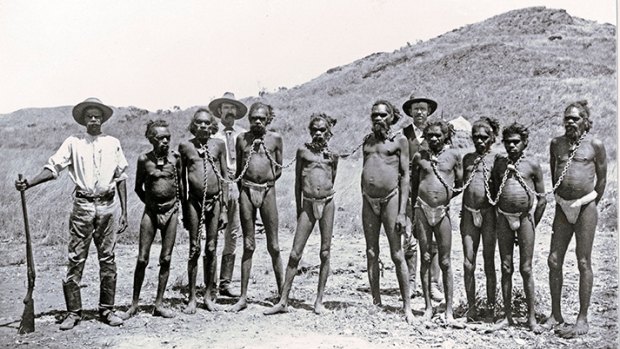 A row of Aboriginal prisoners in chains with two policemen.