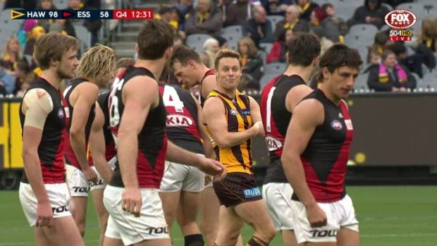 Sam Mitchell gestures towards Essendon players, pretending to inject himself in the arm.
